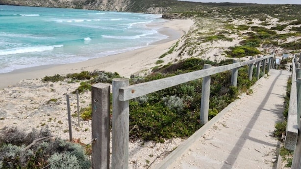 A coastal walkway with a wooden fence, leading to a beach with clear turquoise waters and sandy shores. - Sunset Hideaway - In Kingscote (Kingscote)