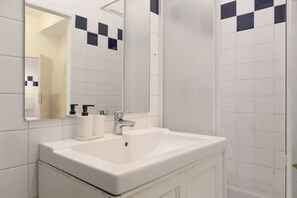 A bathroom with a white sink, a mirror, and black and white tiles. - Superior 2BR Apartment - perfect for 7 persons (Vienna)