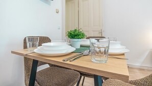 Una mesa de comedor dispuesta con platos, vasos, cubiertos y una pequeña planta en maceta.