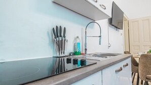 Una cocina moderna con un lavamanos de acero inoxidable, un horno empotrado y un televisor de pantalla plana montado sobre la encimera.