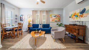 Un salon avec un canapé bleu, une table basse en bois et un ventilateur de plafond.