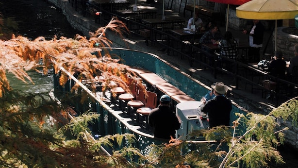 Un restaurant situé au bord de la rivière, avec une terrasse et des parasols.