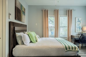 A bedroom with a bed, a desk, and a chair.