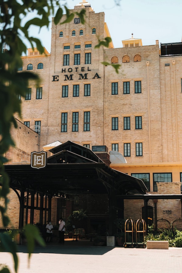 Ein großes, historisches Gebäude mit einem markanten Schild, auf dem "Hotel Emma" steht. Es zeichnet sich durch einen klassischen Baustil mit zahlreichen Fenstern und einem zentralen Turm aus.