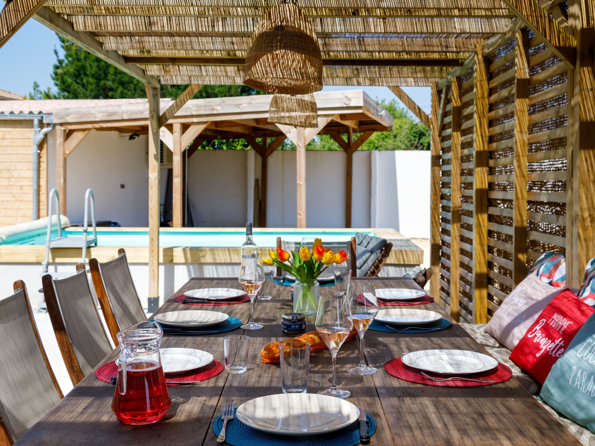 Un área de comedor al aire libre con una piscina al fondo.