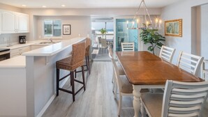 Una cocina moderna con armarios blancos, una mesa de comedor de madera y vistas al exterior.