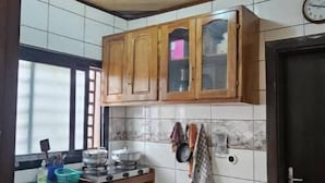 Une cuisine avec des meubles de rangement en bois, un dosseret carrelé, une cuisinière et une fenêtre.