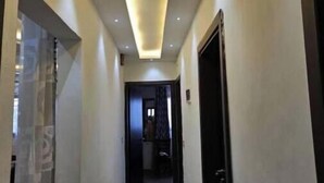Un couloir étroit doté d’un plafond au design moderne et d’un éclairage encastré.