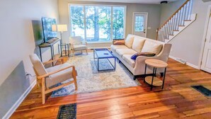 Una sala de estar con sofá, sillones, una mesa de centro y televisor.