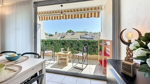 Un balcón con una mesa, sillas y una pequeña mesa con un bol y una botella.
