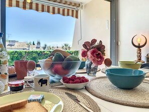 Une table de petit-déjeuner avec vue sur le paysage urbain, notamment sur un immeuble avec un toit recouvert de tuiles.