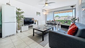 Una sala de estar moderna con televisor de pantalla plana, comedor y balcón con vistas a la ciudad.