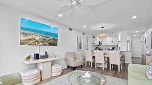 Una sala de estar moderna con un televisor grande, un comedor y una cocina.