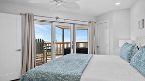 Un dormitorio con una cama grande, ventilador de techo y balcón con vistas.
