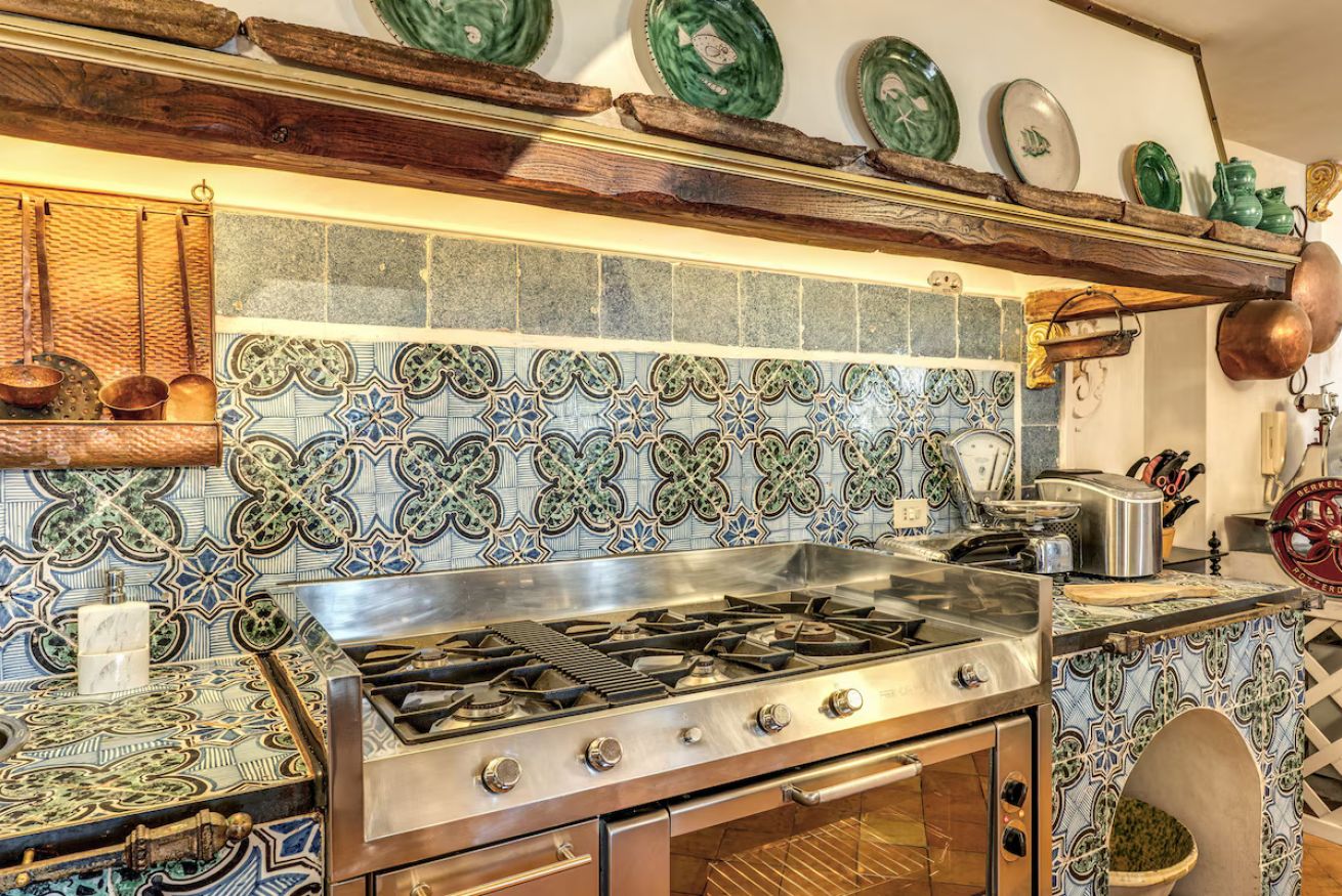 A kitchen with a gas stove, oven, and decorative tiles.