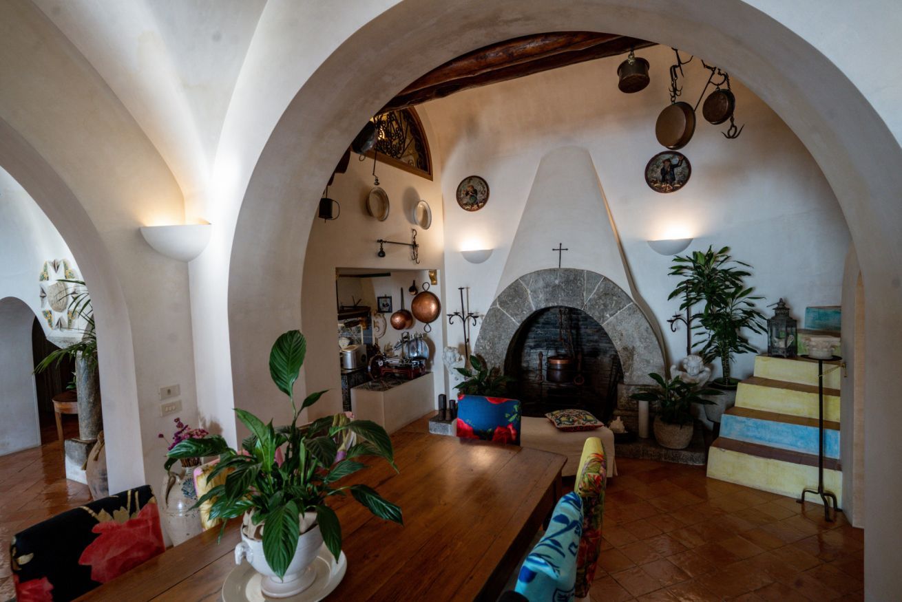 Amplia sala de estar con chimenea, piso de madera y techo abovedado alto.