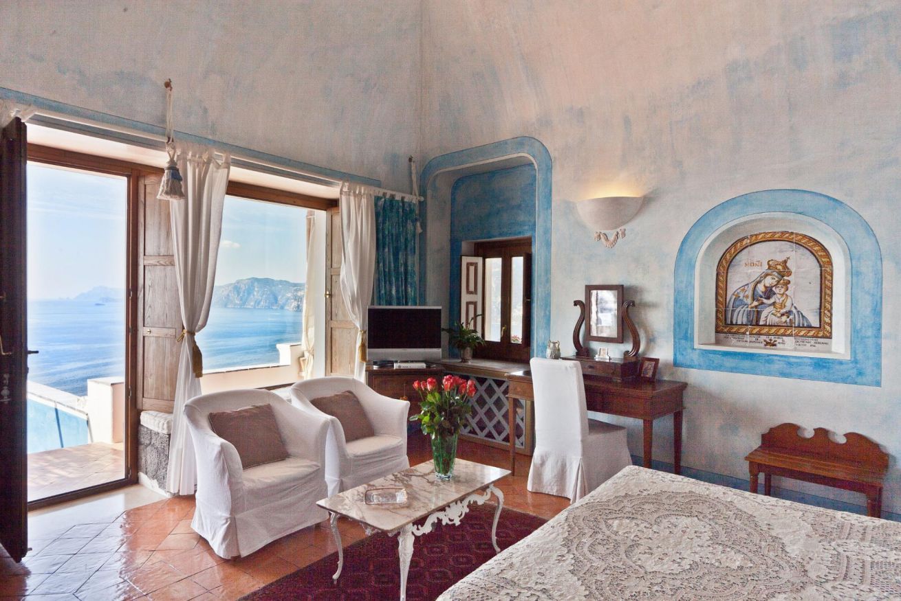 Quarto com vista para o mar, um sofá, uma mesa e um quadro na parede.