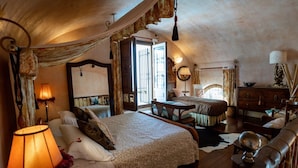 A cozy bedroom with a large bed, a wooden dresser, and a desk.