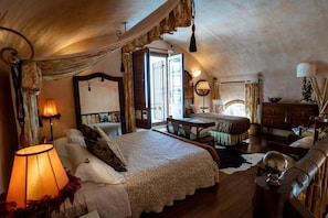 A cozy bedroom with a large bed, a wooden dresser, and a desk.