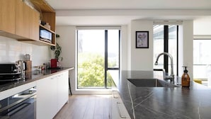 Een moderne keuken met een groot raam, een spoelbak en een magnetron.