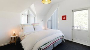 A bedroom with a bed, bedside lamps, a window, and a door.