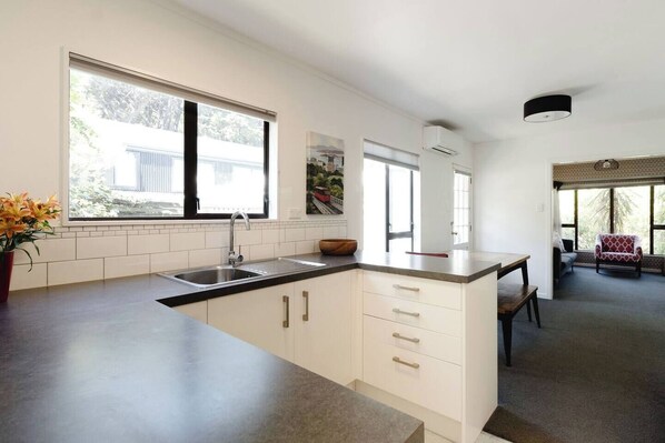 Una cucina moderna con una grande isola, mobili bianchi e vista sull'esterno tramite ampie finestre.