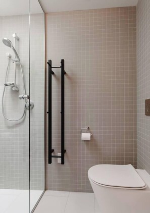 A modern bathroom with a glass shower enclosure, a black towel rack, and a toilet.