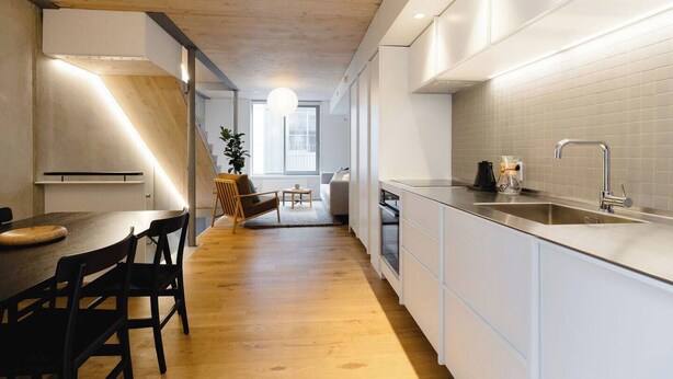 A modern kitchen with white cabinetry, a wooden dining table, and a built-in oven. - Urban Oasis | Spacious 3BR Townhouse w Terrace (Wellington)