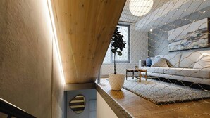 A modern interior with a wooden ceiling, a white sofa, a small table, and a potted plant. - Urban Oasis | Spacious 3BR Townhouse w Terrace (Wellington)