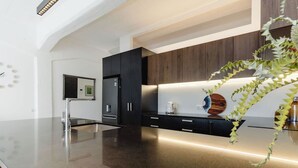 A modern kitchen with a sleek black countertop, stainless steel appliances, and a wooden backsplash.