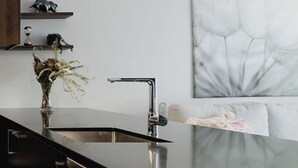 A modern kitchen with a black countertop, stainless steel appliances, and a decorative vase.