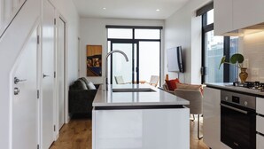 A modern kitchen with a central island, a built-in oven, and a large window. - Chic 2BR Apartment | Secure Gated Complex in CBD (Wellington)