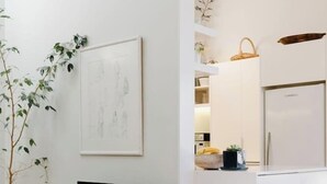 Un salon moderne avec un téléviseur à écran plat, un fauteuil blanc à la fourrure douce et une plante.