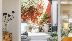 Un coin repas comprenant une table, des chaises et donnant sur un jardin aux feuillages rouges.