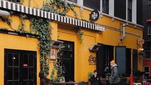 A street-side restaurant with outdoor seating, a black and white striped awning, and a sign for 'J.B.Q. Little Beer Quarter'. - Spacious 2BR Oasis in Central Wellington w Terrace (Auckland)