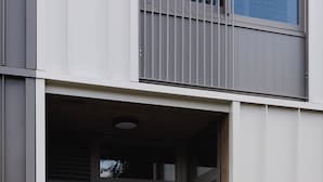Une entrée moderne avec une porte en verre et une enseigne indiquant les numéros d’appartement 198A et 198B.