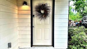 A front door with a wreath, a welcome mat, and a porch light. - Southern Solace (Newnan)