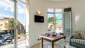 A modern apartment with a balcony, a dining area with a table set for four, and a living room with a sofa. - Bellavista by Interhome (Marina di Andora)