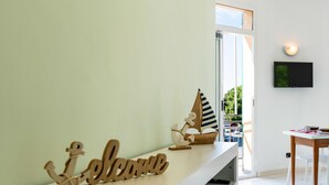 A reception area with a 'Welcome' sign, a small sailboat decoration, and a TV mounted on the wall. - Bellavista by Interhome (Marina di Andora)