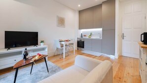 Un salon moderne avec un téléviseur à écran plat, un canapé blanc et une table basse en bois.