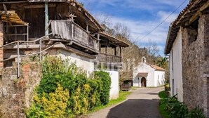 A narrow street with rustic buildings, a white church, and a wooden balcony. - La Casina del Rincón - country house in Riocaliente (Llanes) (Jareras)