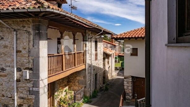 A narrow street with stone buildings, a wooden balcony, and a clear sky. - La Casina del Rincón - country house in Riocaliente (Llanes) (Jareras)