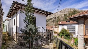 A narrow stone pathway leading to a white building with a wooden balcony. - La Casina del Rincón - country house in Riocaliente (Llanes) (Jareras)