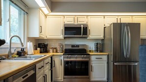 Eine moderne Küche mit weißen Schränken, Edelstahlgeräten und einer Holzausziehtafel.