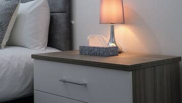 Una camera da letto moderna con un letto, comodino, lampada e un quadro appeso al muro.