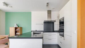 A modern kitchen with white cabinets, a black countertop, and a built-in oven. - Blueground | Senningerberg, balcony, nr Parc de Merl (Luxembourg)