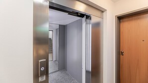 An elevator with a metallic finish, a wooden door, and a carpeted floor. - Blueground | Senningerberg, balcony, nr Parc de Merl (Luxembourg)