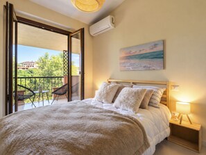 A bedroom with a bed, a nightstand, a lamp, and a painting of a beach scene.
