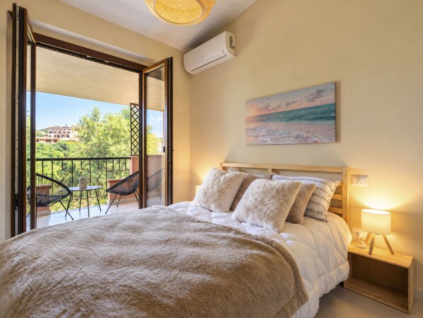 A bedroom with a bed, a nightstand, a lamp, and a painting of a beach scene.