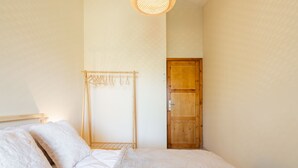 A bedroom with a bed, a wooden wardrobe, and a clothes drying rack.